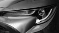 Greyscale closeup of a grey modern car headlight under the lights Royalty Free Stock Photo