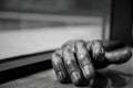 Greyscale closeup shot of wooden human's hand on table with its shadow on blurry background