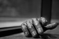 Greyscale closeup shot of wooden human's hand on a table with its shadow on a blurry background