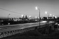 Greyscale horizontal shot of a highway with street lights and high buildings at night time