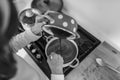 Greyscale image of woman cooking pouring chocolate cream from a