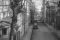 Greyscale of the narrow city streets surrounded by brick buildings and cars, Liepaja, Latvia