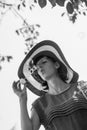 Greyscale portrait of an attractive woman in a wide brimmed sunhat blowing bubbles