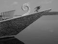 Greyscale shot of a boat with the statue of a bird on it captured on a sunny day