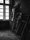 Greyscale shot of broken windows in a creepy abandoned room inside of a building