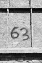 Greyscale shot of a concrete wall with the number sixty-three on it Royalty Free Stock Photo