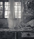 Greyscale shot of the curtains on the window in an old and abandoned room with worn-out walls