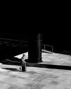 Greyscale shot of an elderly female walking across a plaza in the financial district