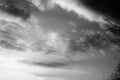 Greyscale shot of the ethereal sky with dark, billowing clouds above a rural road Royalty Free Stock Photo