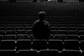 Greyscale shot of a person standing in an empty theatre - concept: loneliness