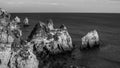 Greyscale shot of the sea rock cliffs with a cloudy sky