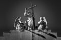 Greyscale shot of statues of three angels holding the Christan cross