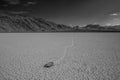 Greyscale shot of stone at the end of a trace surrounded by high rocky hills in Death Valley, USA