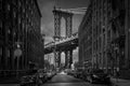 Greyscale of urban buildings and parked cars with Manhattan Bridge in the background Royalty Free Stock Photo