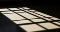 A grid-like shadow pattern is cast on a dark surface, formed by sunlight shining Royalty Free Stock Photo