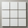 A grid of nine small, white ceramic tiles laid out in a three-by-three pattern on a smooth Royalty Free Stock Photo