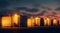 Grid scale battery energy storage system BESS container yard dusk with glowing modules and security fence creating dramatic warm Royalty Free Stock Photo