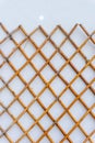 Grid of wooden fence isolated against old white wall background Royalty Free Stock Photo