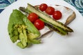 Griddled asparagus with cherry tomatoes alongside avocado on sourdough toast with a layer of cauliflower mousse. All served on a