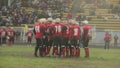 Gridiron football team standing in circle, discussing game strategy in field