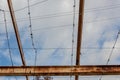 Gridwork of overhead beams, painted and rusted, against a blue sky