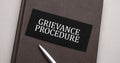 grievance procedure sign written on the black sticker on the brown notepad. Tax concept