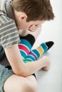 Grieving boy sitting cross legged covers his eyes