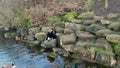 Grieving Filipino female scattering the cremated ashes of her british husband at lake