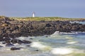 Rugged, rocky shore of Griffiths Island with Port Fairy Lighthouse in the background in Victoria, Australia. Royalty Free Stock Photo