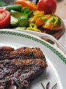 Grill Beef steak with a sprig of rosemary in a white plate. Entrecote. Rib-eye. Coarsely chopped fresh vegetables as a garnish Royalty Free Stock Photo