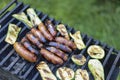 Grill family time. People grilling sausages and vegetables on a modern grill outdoors at sunet, close-up. Royalty Free Stock Photo