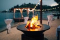 Grill with flames inside. Round table-cooking surface. On the beach, in the background of the gazebo by the water with