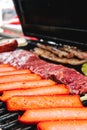 Grill full of sausages, meats and vegetables about to grill.