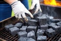 grill gloves placing charcoals in a pyramid formation for barbecue