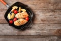 Grill pan with fried chicken breast and garnish on wooden background, top view. Royalty Free Stock Photo