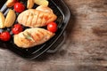 Grill pan with fried chicken breast and garnish on wooden background, top view. Royalty Free Stock Photo