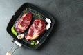 Grill pan with pieces of fresh beef meat, thyme and spices on gray table, top view. Space for text Royalty Free Stock Photo