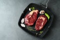 Grill pan with pieces of fresh beef meat, thyme and spices on gray table, top view. Space for text Royalty Free Stock Photo