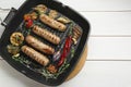 Grill pan with tasty sausages and vegetables on white wooden table, top view. Space for text Royalty Free Stock Photo