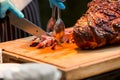 Grill restaurant kitchen. Chef in Blue cooking gloves using knife to cut smoked pork. Roast pork neck. Roasted shoulder of pork on Royalty Free Stock Photo