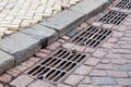 Grille of the drainage system manhole on the paving road. Royalty Free Stock Photo