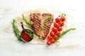 Grilled aged T-bone steak with rosemary on a white wooden background. Top view. Rustic style