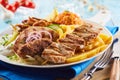 Grilled assorted meat on a plate with fried chips