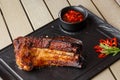 Grilled and barbecue hot pork ribs with hot chilli pepper and hot sauce on black stone background. Isolated. Dish for Royalty Free Stock Photo