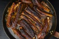 Grilled barbecue pork ribs, in frying cast iron pan, on black stone background, top view flat lay Royalty Free Stock Photo