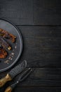 Grilled barbecue pork ribs, on plate, with barbeque knife and meat fork, on black wooden table background, top view flat lay, with Royalty Free Stock Photo