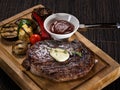 Grilled beef angus steak with melted butter on a wooden cutting board served with grilled vegetables, close up photo on a dark Royalty Free Stock Photo