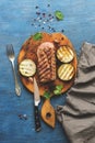 Grilled beef meat medium rare on a cutting board with spices, blue rustic background. Top view, copy space