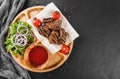 Grilled beef meat and vegetables with fresh salad and bbq sauce on cutting board over black stone background. Hot Meat Dishes Royalty Free Stock Photo