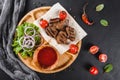 Grilled beef meat and vegetables with fresh salad and bbq sauce on cutting board over black stone background Royalty Free Stock Photo